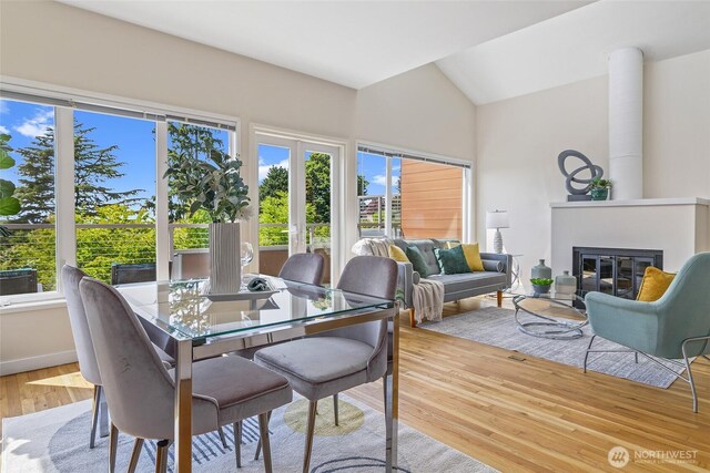 101 NW 58th St Unit 9, Seattle, WA 98107 - dining space with light wood-style flooring, a glass covered fireplace, lofted ceiling, and baseboards