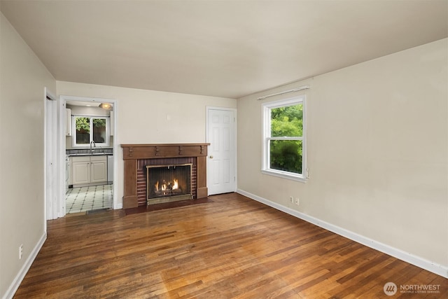 6522 42nd Ave NE, Seattle, WA 98115 - unfurnished living room with wood finished floors, a brick fireplace, baseboards, and a sink