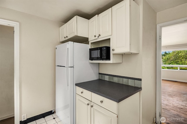 6522 42nd Ave NE, Seattle, WA 98115 - kitchen with black microwave, dark countertops, freestanding refrigerator, and white cabinetry