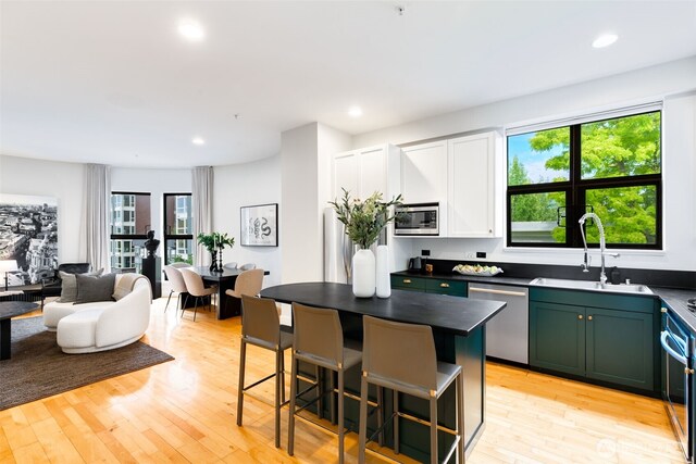 615 E Pike St Unit 306, Seattle, WA 98122 - kitchen featuring stainless steel appliances, a kitchen bar, green cabinets, dark countertops, and light wood-type flooring