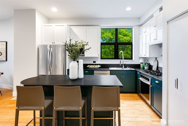 615 E Pike St Unit 306, Seattle, WA 98122 - kitchen featuring stainless steel appliances, dark countertops, white cabinets, light wood-style floors, and recessed lighting