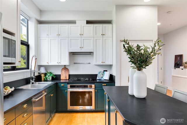 615 E Pike St Unit 306, Seattle, WA 98122 - kitchen with stainless steel appliances, dark countertops, white cabinets, light wood finished floors, and recessed lighting