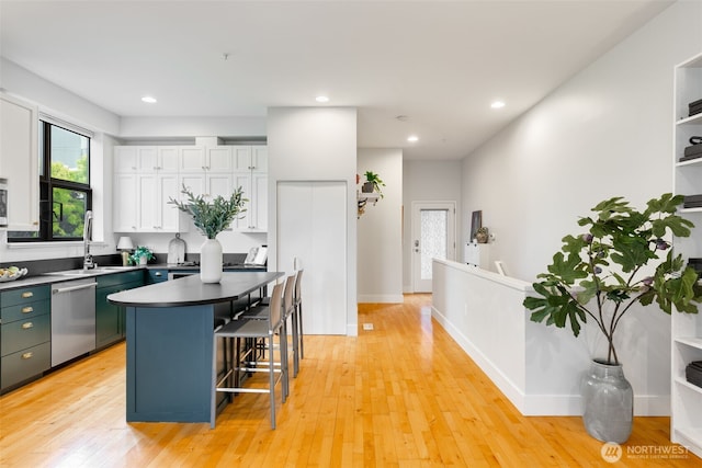 615 E Pike St Unit 306, Seattle, WA 98122 - kitchen featuring dishwasher, a breakfast bar area, white cabinets, a center island, and light wood-style flooring