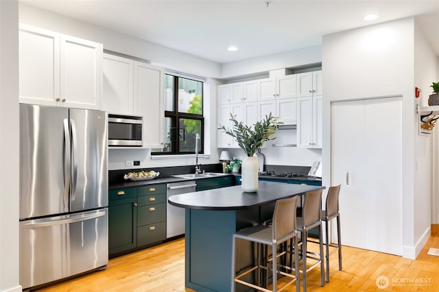 615 E Pike St Unit 306, Seattle, WA 98122 - kitchen featuring stainless steel appliances, dark countertops, a kitchen bar, white cabinets, and light wood-type flooring