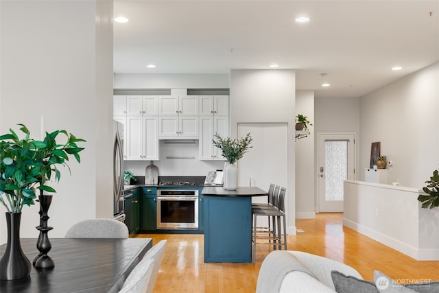 615 E Pike St Unit 306, Seattle, WA 98122 - kitchen with stainless steel appliances, dark countertops, light wood-style flooring, white cabinets, and recessed lighting