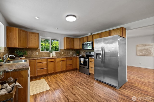 1315 SW 310th St, Federal Way, WA 98023 - kitchen with appliances with stainless steel finishes, a sink, decorative backsplash, brown cabinets, and light wood-style floors