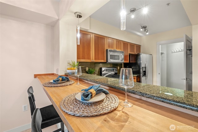 1545 NW 57th St Unit 220, Seattle, WA 98107 - kitchen with appliances with stainless steel finishes, tasteful backsplash, brown cabinetry, track lighting, and pendant lighting
