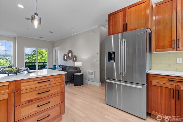 31 Etruria St Unit B, Seattle, WA 98109 - kitchen with stainless steel fridge with ice dispenser, ornamental molding, tasteful backsplash, brown cabinetry, and light countertops