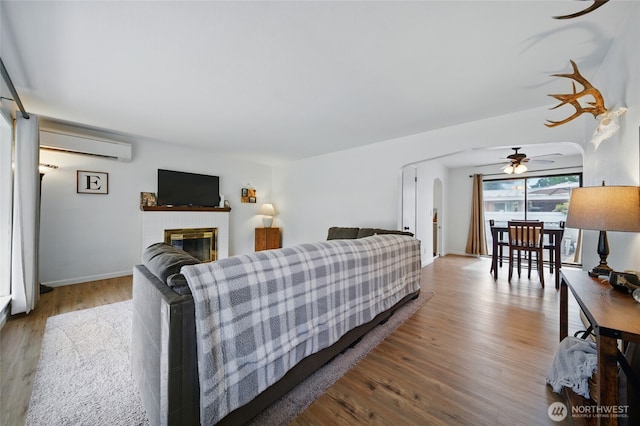 1511 Howard St, Walla Walla, WA 99362 - living room with a wall unit AC, a ceiling fan, wood finished floors, a fireplace, and arched walkways