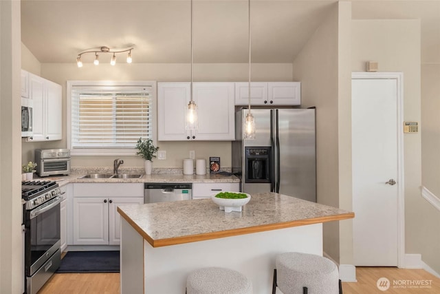 12422 2nd Ave SW, Burien, WA 98146 - kitchen with stainless steel appliances, a sink, a breakfast bar, light wood-style floors, and white cabinets