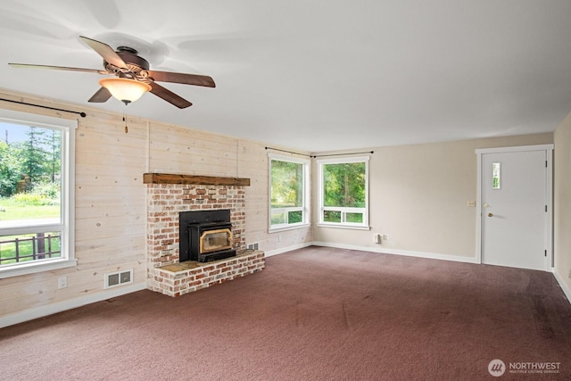 924 1st St, Sultan, WA 98294 - unfurnished living room featuring a wood stove, plenty of natural light, a ceiling fan, baseboards, and wood walls
