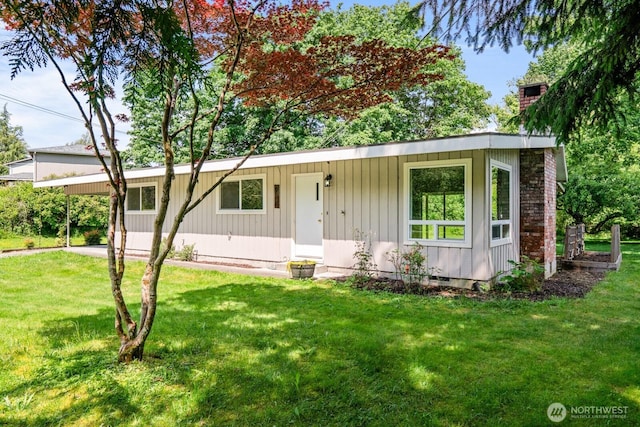 924 1st St, Sultan, WA 98294 - view of front of home featuring a front lawn, a chimney, a carport, and board and batten siding