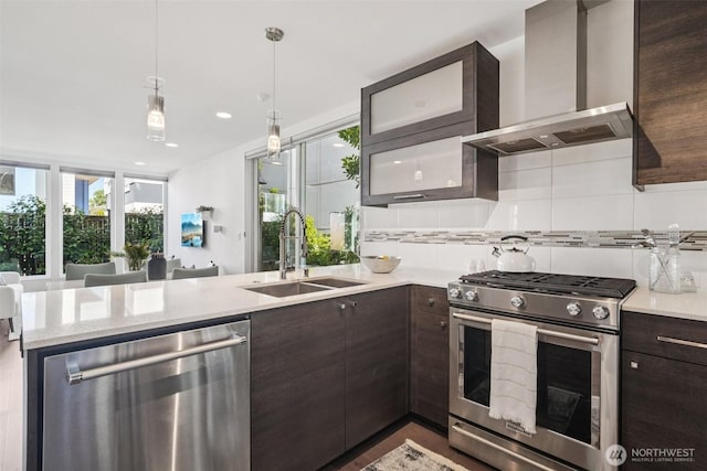 917 29th Ave S, Seattle, WA 98144 - kitchen with stainless steel appliances, wall chimney range hood, dark brown cabinets, tasteful backsplash, and a peninsula