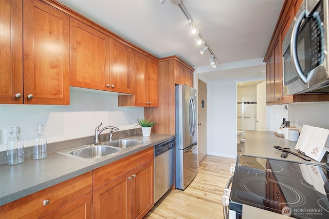 919 2nd Ave W Unit 601, Seattle, WA 98119 - kitchen with stainless steel appliances, brown cabinetry, a sink, and light wood-style flooring