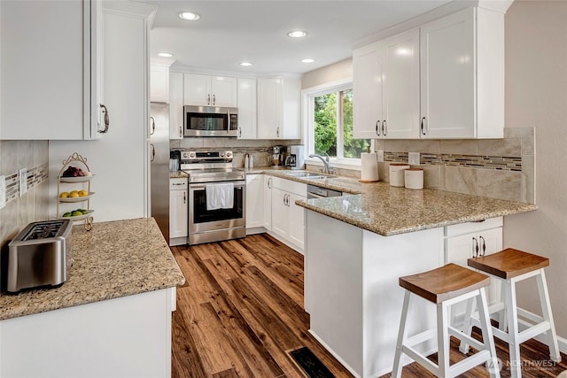 13303 53rd Ave SE, Everett, WA 98208 - kitchen with appliances with stainless steel finishes, a sink, a peninsula, white cabinetry, and backsplash