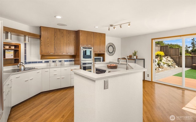 4142 52nd Ave SW, Seattle, WA 98116 - kitchen with double oven, light wood finished floors, black electric cooktop, light countertops, and recessed lighting