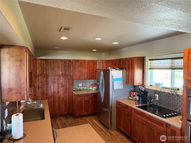 8708 Rd K Rd NE, Moses Lake, WA 98837 - kitchen featuring black electric stovetop, stainless steel fridge with ice dispenser, light wood finished floors, light countertops, and brown cabinetry
