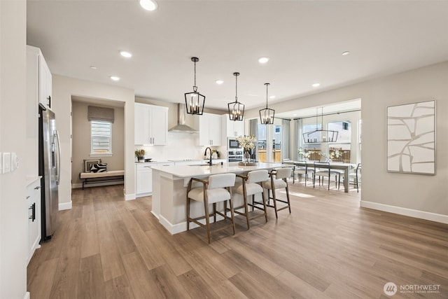 13920 181st St E Unit 64, Puyallup, WA 98374 - kitchen with wall chimney exhaust hood, stainless steel refrigerator with ice dispenser, a chandelier, light wood-type flooring, and recessed lighting