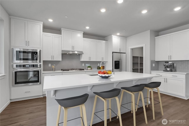 2609 S 7th Way, Ridgefield, WA 98642 - kitchen with stainless steel appliances, under cabinet range hood, decorative backsplash, dark wood-style floors, and recessed lighting