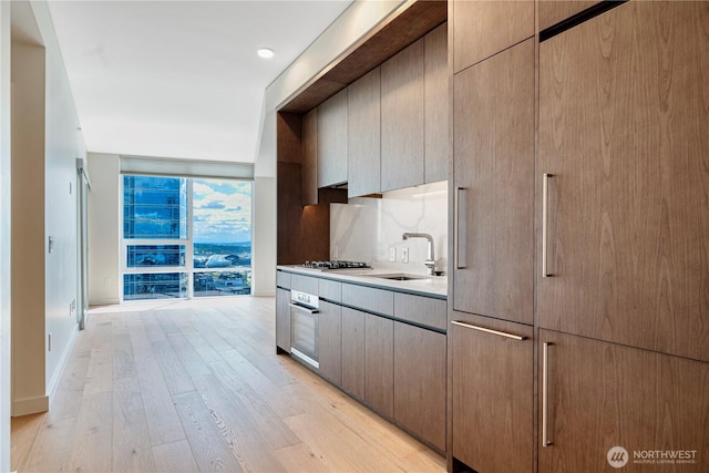 121 Stewart St Unit 3004, Seattle, WA 98101 - kitchen with a sink, appliances with stainless steel finishes, light wood-style flooring, a wall of windows, and light countertops
