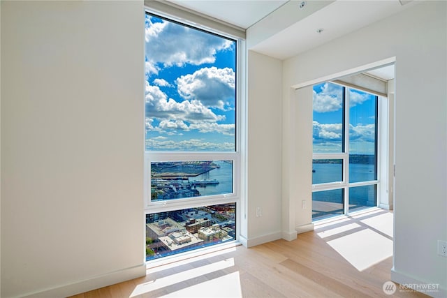 121 Stewart St Unit 3004, Seattle, WA 98101 - empty room with light wood-style flooring, a water view, and baseboards