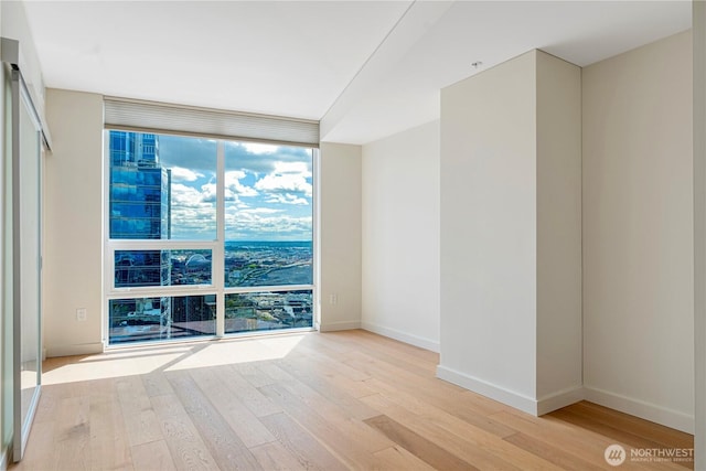 121 Stewart St Unit 3004, Seattle, WA 98101 - empty room featuring a wall of windows, light wood finished floors, and baseboards