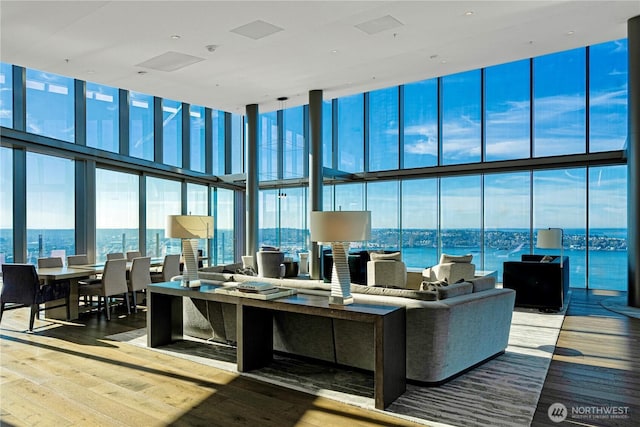 121 Stewart St Unit 3004, Seattle, WA 98101 - living area with a wall of windows, a towering ceiling, hardwood / wood-style flooring, and a water view