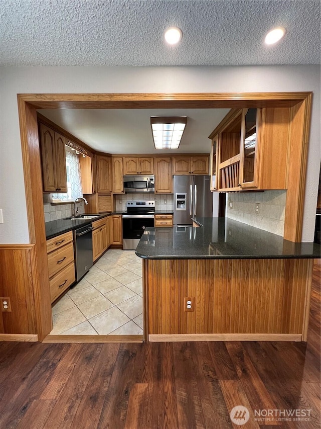 2116 E 65th St, Tacoma, WA 98404 - kitchen featuring appliances with stainless steel finishes, a peninsula, a sink, glass insert cabinets, and backsplash