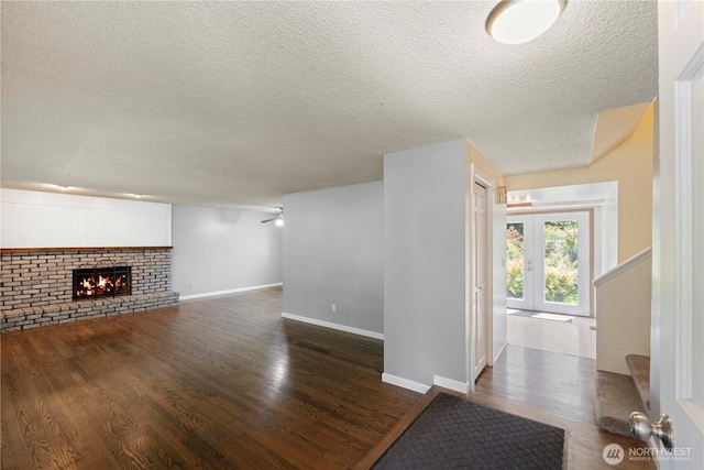 28713 SE 462nd Pl, Enumclaw, WA 98022 - unfurnished living room featuring a textured ceiling, dark wood-style floors, a brick fireplace, baseboards, and stairs