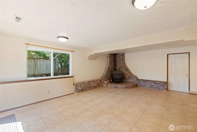 28713 SE 462nd Pl, Enumclaw, WA 98022 - unfurnished living room with a wood stove, tile patterned floors, baseboards, and a textured ceiling