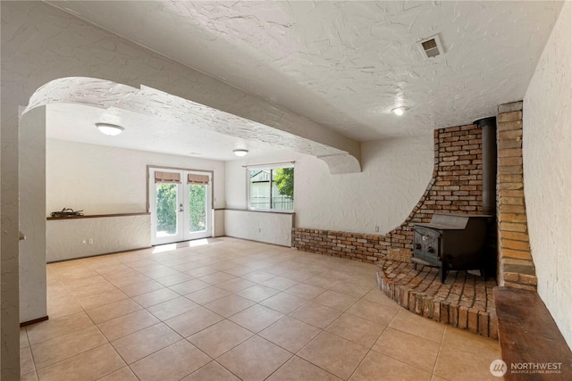 28713 SE 462nd Pl, Enumclaw, WA 98022 - unfurnished living room featuring french doors, a textured ceiling, tile patterned flooring, a wood stove, and a textured wall