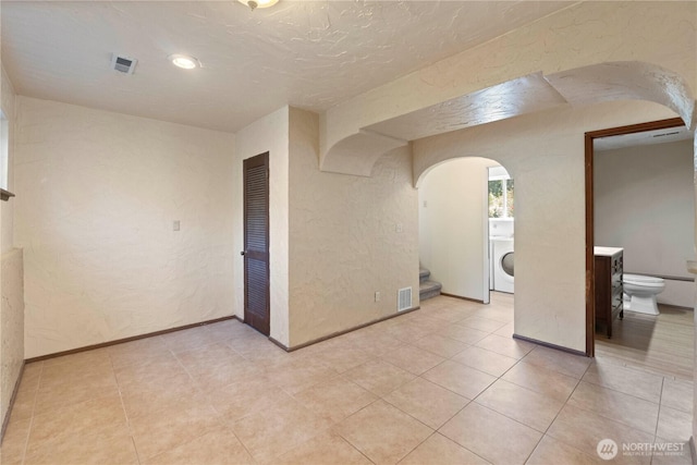 28713 SE 462nd Pl, Enumclaw, WA 98022 - unfurnished room featuring washer / clothes dryer, arched walkways, a textured wall, stairway, and light tile patterned floors