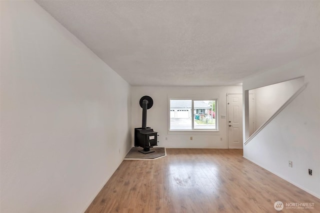 1702 C St SE, Auburn, WA 98002 - unfurnished living room with a wood stove, light wood-style flooring, and baseboards