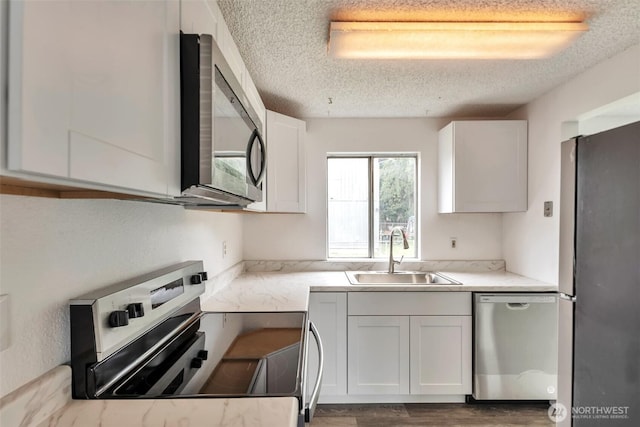 1702 C St SE, Auburn, WA 98002 - kitchen featuring stainless steel appliances, a sink, a textured ceiling, white cabinetry, and wood finished floors