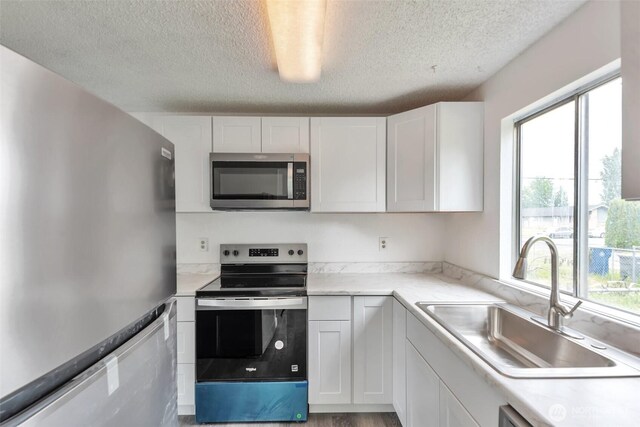 1702 C St SE, Auburn, WA 98002 - kitchen with appliances with stainless steel finishes, a sink, a textured ceiling, and white cabinets
