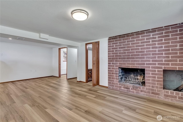31006 38th Ave S, Auburn, WA 98001 - unfurnished living room featuring a brick fireplace, wood finished floors, baseboards, and a textured ceiling