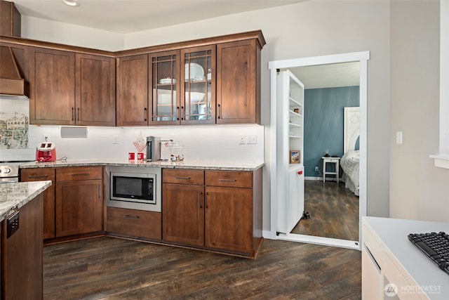 1566 Deer Ridge Rd, Oak Harbor, WA 98277 - kitchen with stainless steel microwave, dark wood-type flooring, backsplash, light stone counters, and glass insert cabinets