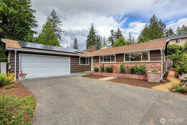 20010 3rd Ave NW, Shoreline, WA 98177 - ranch-style house featuring a garage, driveway, roof mounted solar panels, a chimney, and brick siding
