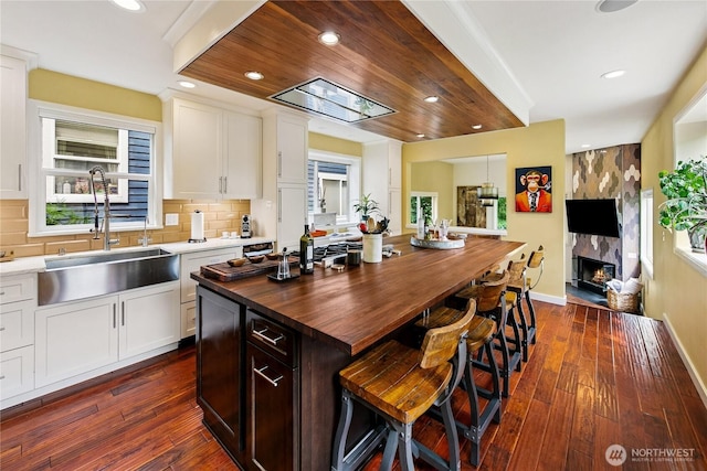 444 26th Ave E, Seattle, WA 98112 - kitchen with butcher block counters, a breakfast bar area, dark wood-style flooring, white cabinetry, and recessed lighting