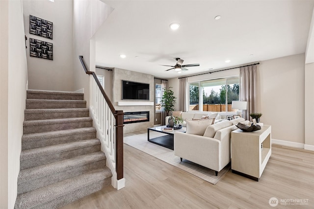 13912 181st St E Unit 62, Puyallup, WA 98374 - living room with a large fireplace, light wood-type flooring, ceiling fan, stairway, and baseboards