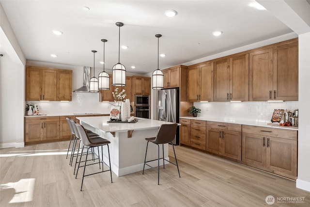 13912 181st St E Unit 62, Puyallup, WA 98374 - kitchen with wall chimney exhaust hood, stainless steel appliances, brown cabinetry, a breakfast bar area, and backsplash