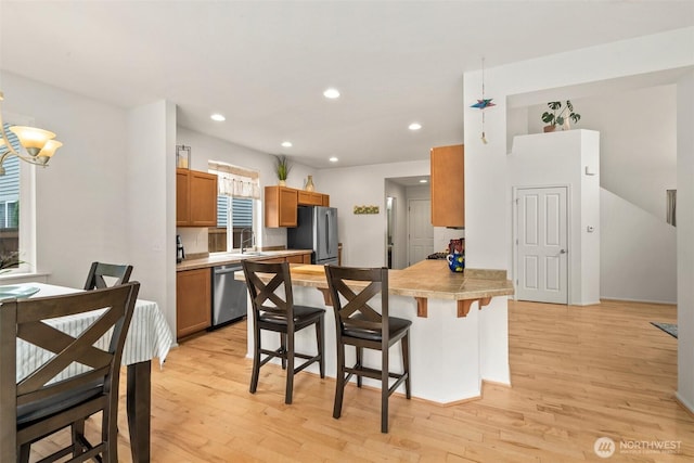 1082 G St SW, Tumwater, WA 98512 - kitchen with stainless steel appliances, a sink, a peninsula, a kitchen bar, and light wood-style floors