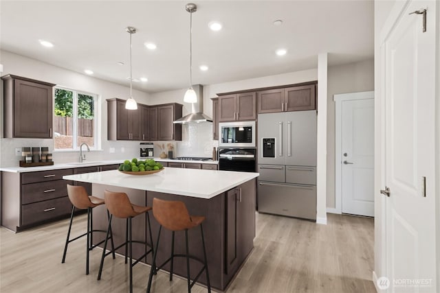 3704 98th Avenue Ct E Unit 1, Edgewood, WA 98371 - kitchen with stainless steel appliances, wall chimney exhaust hood, light wood finished floors, dark brown cabinets, and recessed lighting