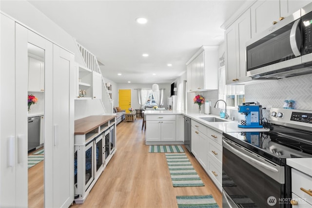 3628S Sheridan Ave, Tacoma, WA 98418 - kitchen featuring appliances with stainless steel finishes, a sink, light wood finished floors, white cabinetry, and recessed lighting