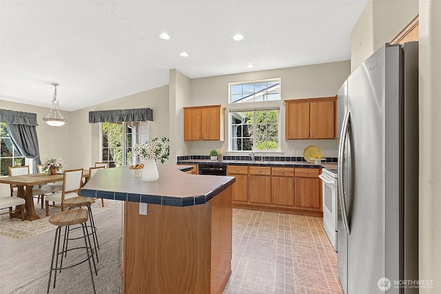 1933 Windflower Ln SE, Lacey, WA 98503 - kitchen with freestanding refrigerator, a sink, brown cabinetry, electric range, and vaulted ceiling