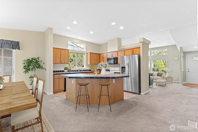 1933 Windflower Ln SE, Lacey, WA 98503 - kitchen with stainless steel fridge with ice dispenser, black microwave, light colored carpet, electric range, and a center island