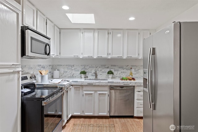 14600 SE 176th St Unit H11, Renton, WA 98058 - kitchen with appliances with stainless steel finishes, a skylight, a sink, light wood-type flooring, and white cabinetry