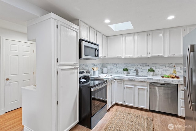 14600 SE 176th St Unit H11, Renton, WA 98058 - kitchen with stainless steel appliances, a skylight, a sink, white cabinets, and recessed lighting