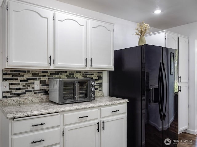 4715 247th St E, Graham, WA 98338 - kitchen with black fridge, tasteful backsplash, white cabinets, and light stone counters