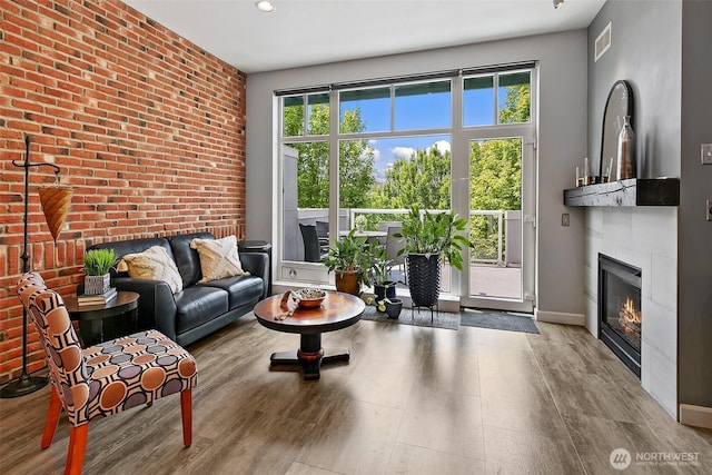 17 W Mercer St Unit 302, Seattle, WA 98119 - living room featuring a glass covered fireplace, wood finished floors, recessed lighting, baseboards, and brick wall